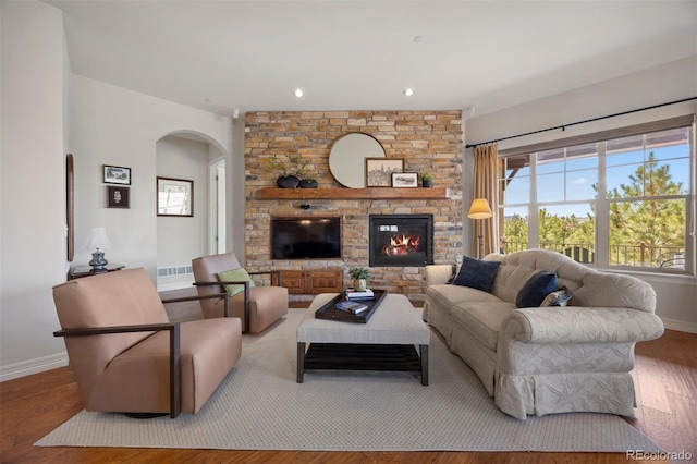 living area with a fireplace, arched walkways, recessed lighting, baseboards, and wood finished floors