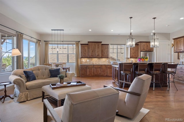 living area with recessed lighting, a notable chandelier, and light wood-type flooring