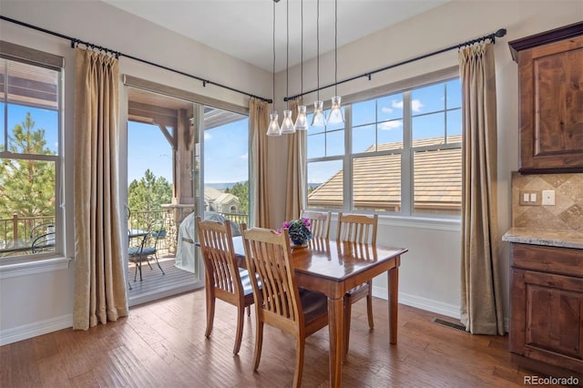 dining area with dark wood-style flooring, baseboards, visible vents, and a chandelier