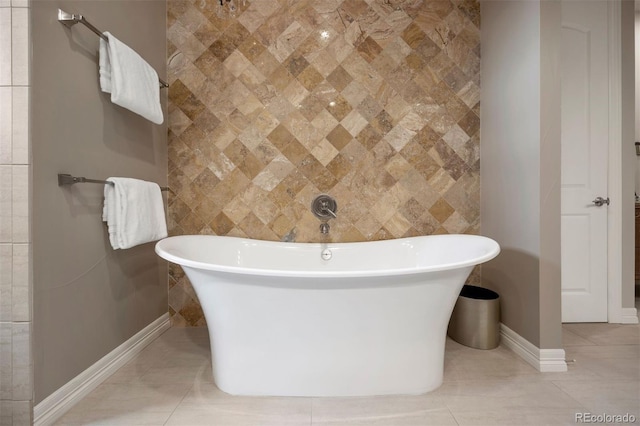 bathroom with a freestanding tub, baseboards, and tile patterned floors