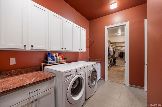 clothes washing area featuring baseboards, cabinet space, washer and dryer, and light colored carpet