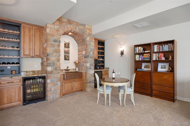 dining space with beverage cooler, wet bar, visible vents, and light carpet