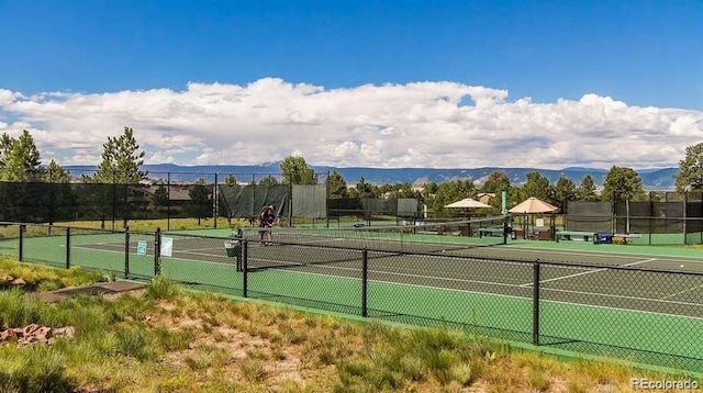 view of tennis court featuring a mountain view and fence
