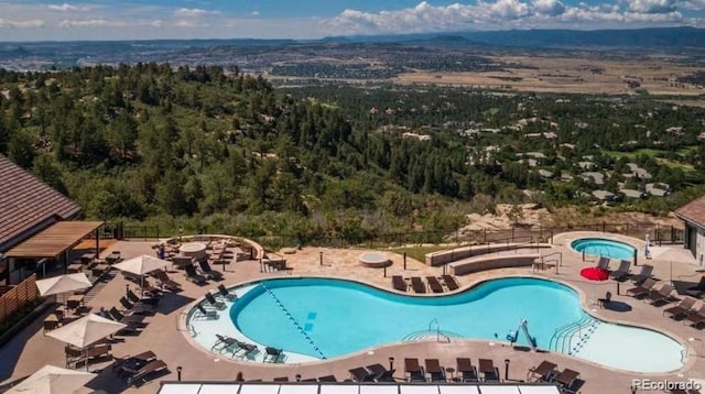 community pool with a wooded view and a patio area