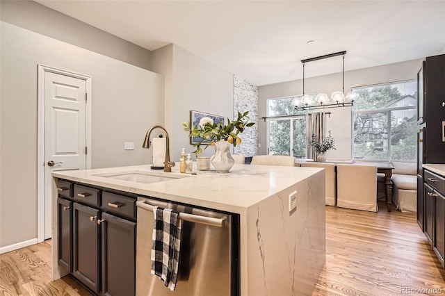 16179 W 70th Pl, Arvada, CO 80007 - kitchen with dishwasher, a sink, light wood finished floors, a chandelier, and light stone countertops