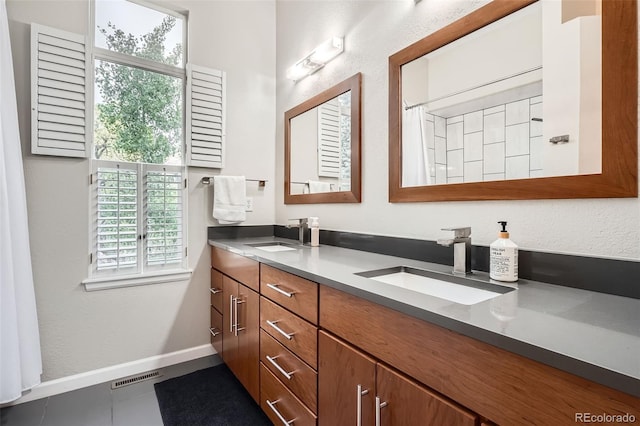 16179 W 70th Pl, Arvada, CO 80007 - bathroom with double vanity, baseboards, a shower with shower curtain, and tile patterned flooring
