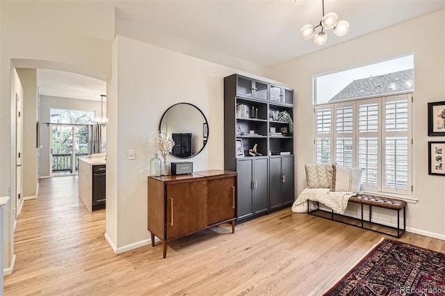 16179 W 70th Pl, Arvada, CO 80007 - living area featuring a chandelier, light wood-type flooring, arched walkways, and baseboards