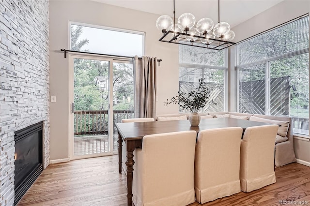 16179 W 70th Pl, Arvada, CO 80007 - dining area with a chandelier, light wood-type flooring, healthy amount of natural light, and a fireplace