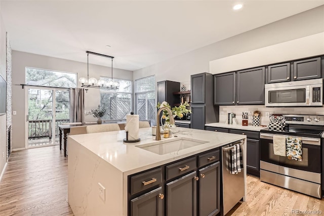 16179 W 70th Pl, Arvada, CO 80007 - kitchen with stainless steel appliances, a sink, a chandelier, light wood finished floors, and healthy amount of natural light