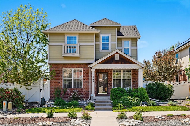 1063 Roslyn Ct, Denver, CO 80230 - view of front facade featuring fence, brick siding, and roof with shingles