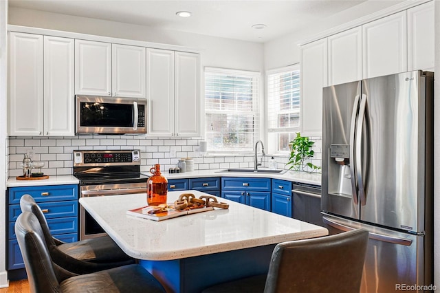 1063 Roslyn Ct, Denver, CO 80230 - kitchen featuring stainless steel appliances, blue cabinets, a sink, a kitchen bar, and white cabinetry