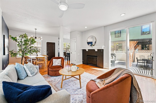 1063 Roslyn Ct, Denver, CO 80230 - living area featuring light wood-style floors, a glass covered fireplace, a ceiling fan, and a textured ceiling