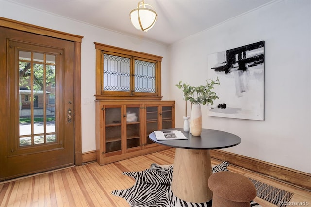foyer entrance featuring light wood-style floors, baseboards, and ornamental molding