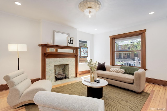 living room with baseboards, a fireplace with raised hearth, light wood finished floors, and recessed lighting