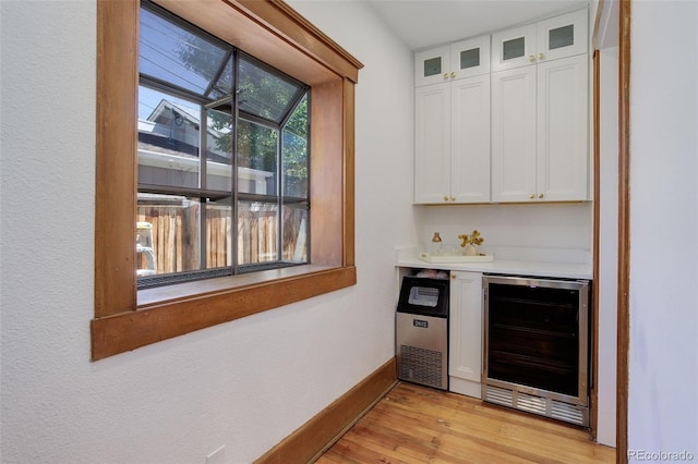 indoor dry bar featuring beverage cooler, light wood-type flooring, and baseboards