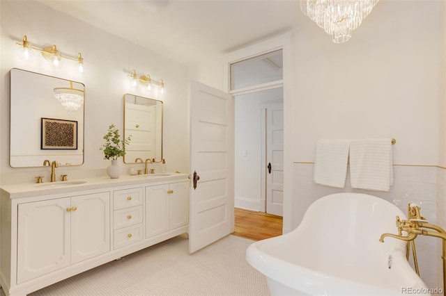bathroom with a soaking tub, a chandelier, and double vanity