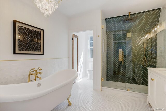 full bathroom featuring a shower stall, a freestanding bath, tile walls, a chandelier, and vanity