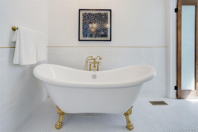 bathroom featuring tile walls, a soaking tub, a wainscoted wall, and tile patterned flooring