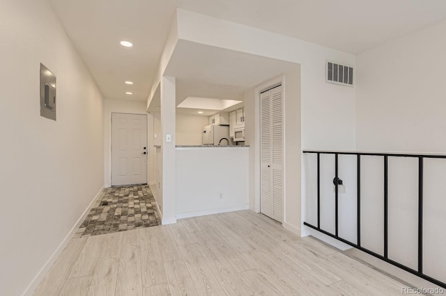 hall with light wood-type flooring and electric panel