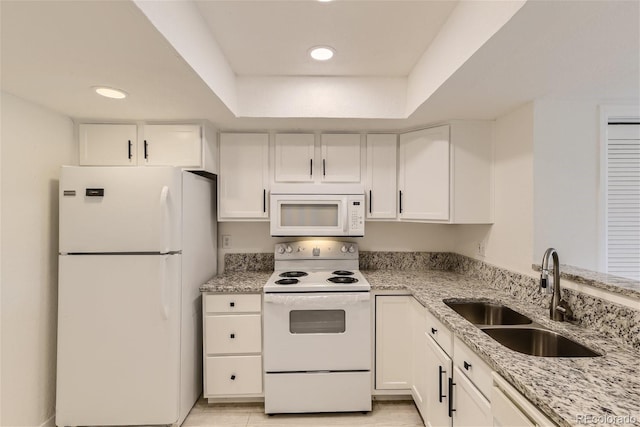 kitchen featuring white appliances, sink, light tile patterned floors, light stone counters, and white cabinetry