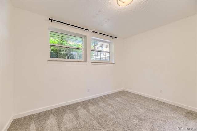 carpeted empty room featuring a textured ceiling