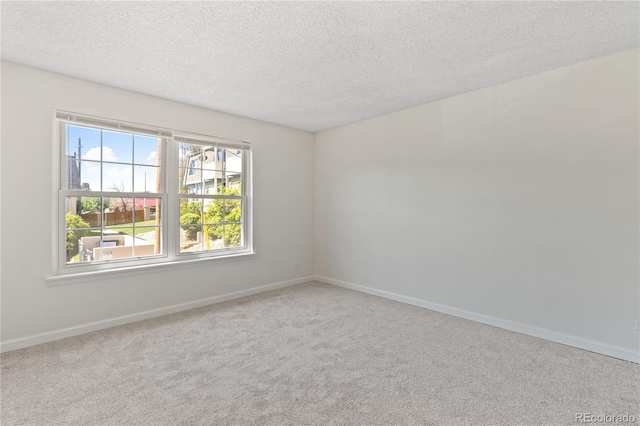 carpeted empty room featuring a textured ceiling and baseboards