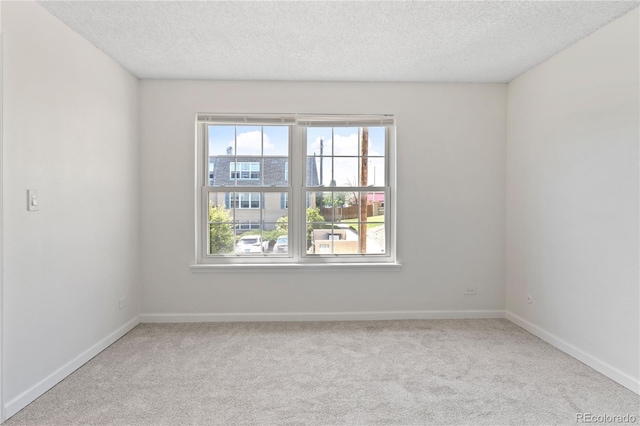 carpeted empty room featuring healthy amount of natural light, a textured ceiling, and baseboards