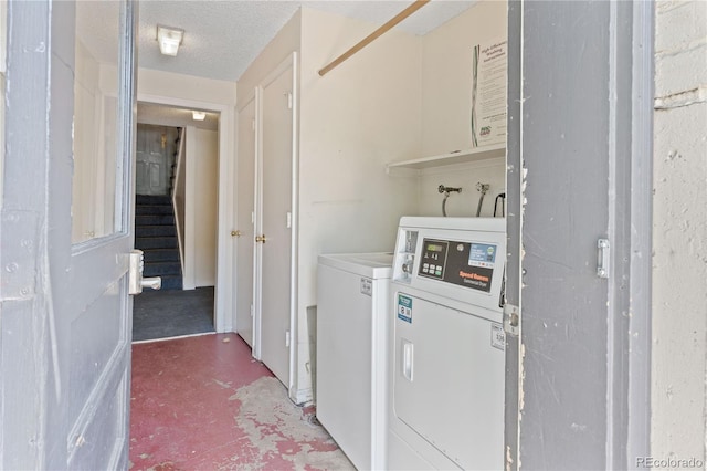 clothes washing area with washer and clothes dryer and a textured ceiling