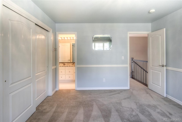 unfurnished bedroom featuring light carpet, ensuite bath, and baseboards