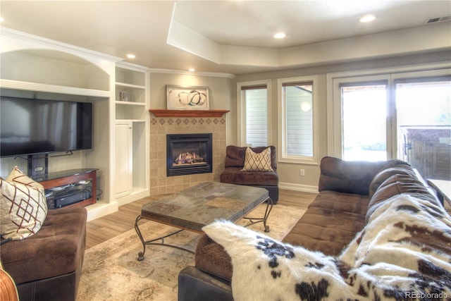 living room with light wood-style flooring, a tiled fireplace, visible vents, and recessed lighting