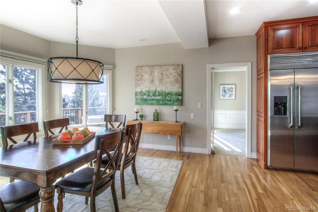 dining room with baseboards, a decorative wall, and light wood-style floors