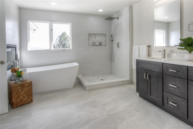 full bath with tiled shower, a soaking tub, tile patterned flooring, and vanity