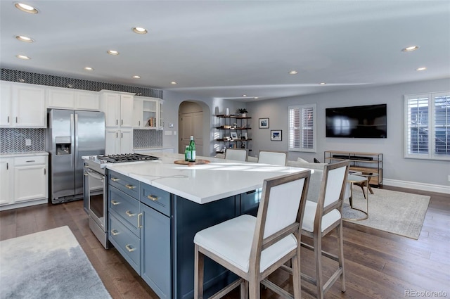 kitchen with blue cabinetry, stainless steel appliances, dark hardwood / wood-style flooring, and white cabinets