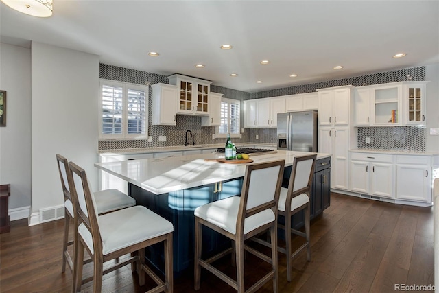 kitchen featuring stainless steel appliances, a kitchen island, dark wood-type flooring, and white cabinets