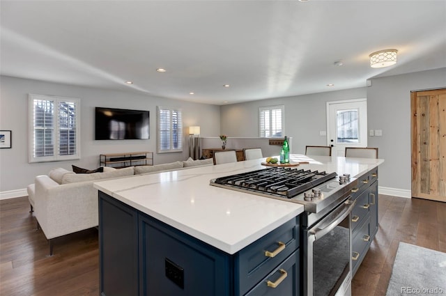 kitchen featuring blue cabinetry, light stone counters, dark hardwood / wood-style floors, stainless steel range with gas stovetop, and a kitchen island