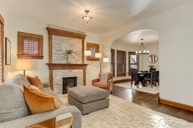 living room featuring a large fireplace, dark hardwood / wood-style floors, and a chandelier