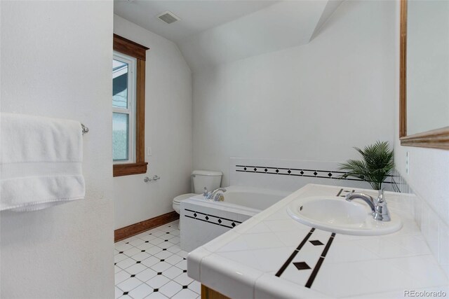 bathroom featuring vanity, toilet, vaulted ceiling, and a bath