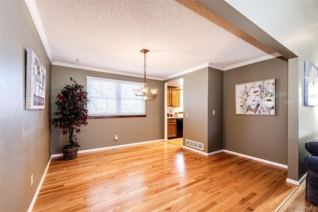 unfurnished dining area with a textured ceiling, light hardwood / wood-style floors, crown molding, and a notable chandelier