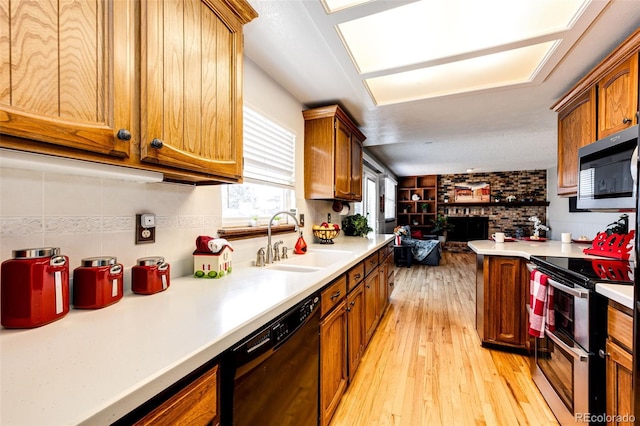 kitchen with a fireplace, sink, light hardwood / wood-style floors, and appliances with stainless steel finishes