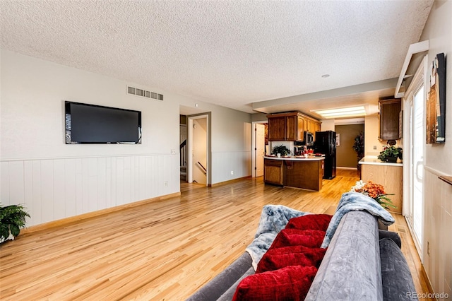 living room featuring a textured ceiling and light hardwood / wood-style flooring