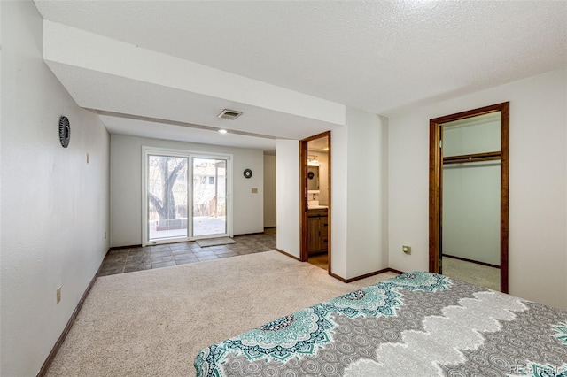 carpeted bedroom with access to exterior, ensuite bathroom, a textured ceiling, a spacious closet, and a closet