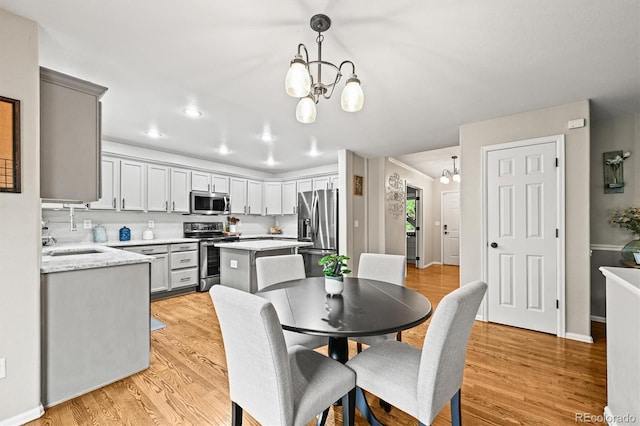 dining space featuring a chandelier, light wood-type flooring, recessed lighting, and baseboards