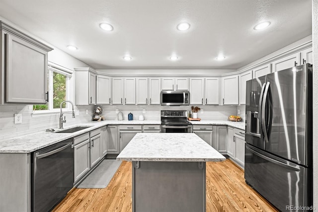 kitchen featuring stainless steel appliances, a sink, gray cabinetry, backsplash, and recessed lighting