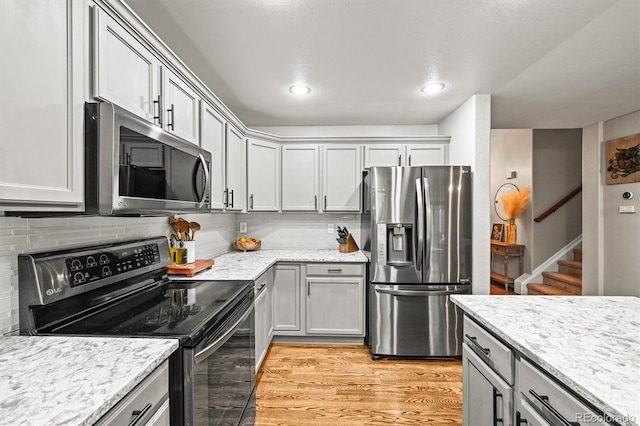 kitchen with appliances with stainless steel finishes, light wood-style flooring, tasteful backsplash, gray cabinetry, and recessed lighting