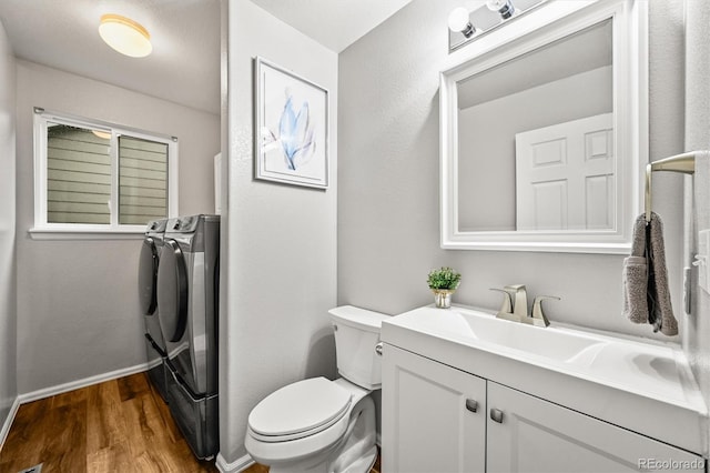 bathroom with washing machine and clothes dryer, wood finished floors, toilet, vanity, and baseboards