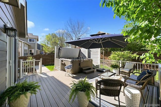 wooden terrace with a hot tub and a fenced backyard