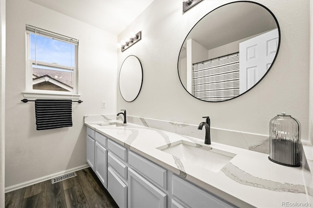 full bathroom featuring wood finished floors, baseboards, and double vanity