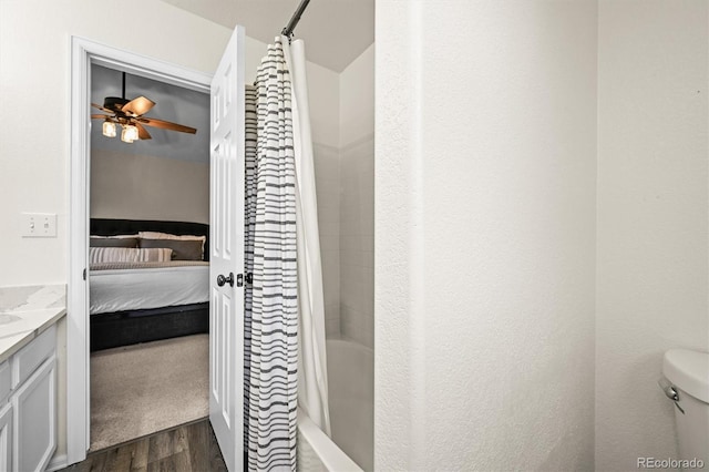 ensuite bathroom featuring wood finished floors, vanity, ceiling fan, and toilet