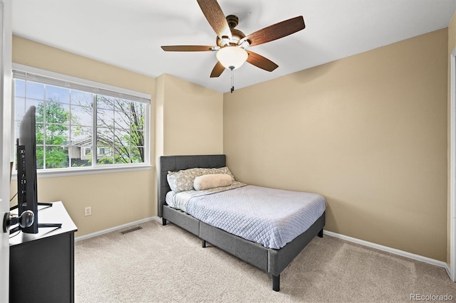 bedroom featuring light colored carpet, baseboards, and a ceiling fan