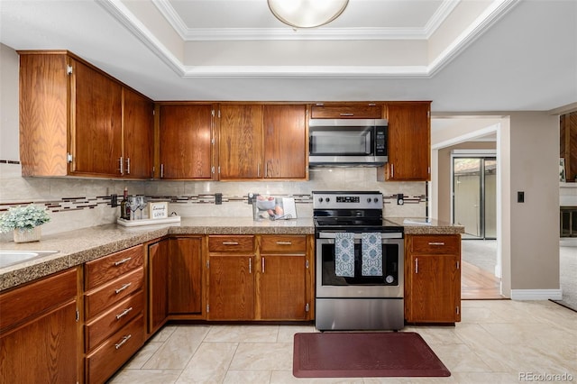 kitchen with decorative backsplash, light tile patterned floors, ornamental molding, a raised ceiling, and appliances with stainless steel finishes